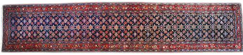 A West Persian runner, the dark indigo field with an all over mina hani design, a madder trailing flower and vine border, 536cm x 109cm.  Illustrated