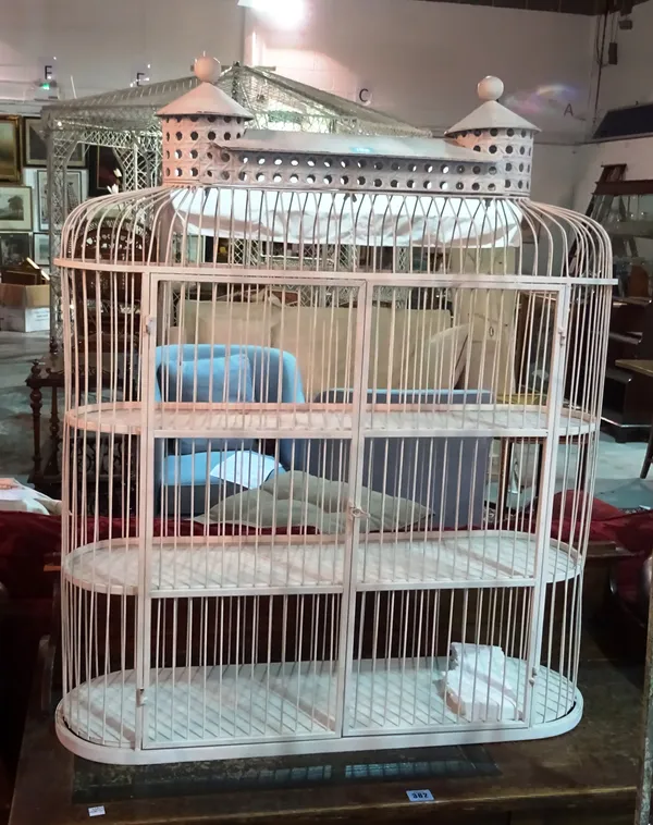 A 20th century white painted metal three tier bird cage, 78cm wide x 95cm high and a large wicker storm lantern, glass liner lacking, (2).  D6