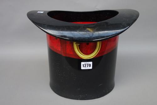 A Fornasetti tole peinte novelty ice bucket, circa 1980, modelled as a top hat with red buckled band, paper label to the base, 25.5cm high.