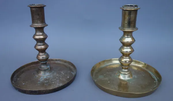 An 18th century bell metal brass candlestick of turned form, on a wide plan circular base, and another later similar candlestick, 13cm high, (2).