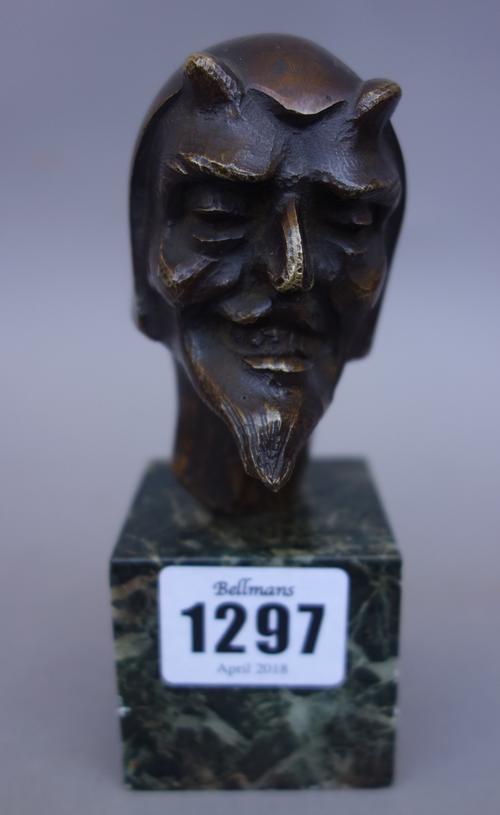 A Continental bronze bust, early 20th century, depicting the Devil, indistinctly signed and mounted on a green vein marble plinth, 13cm high, together