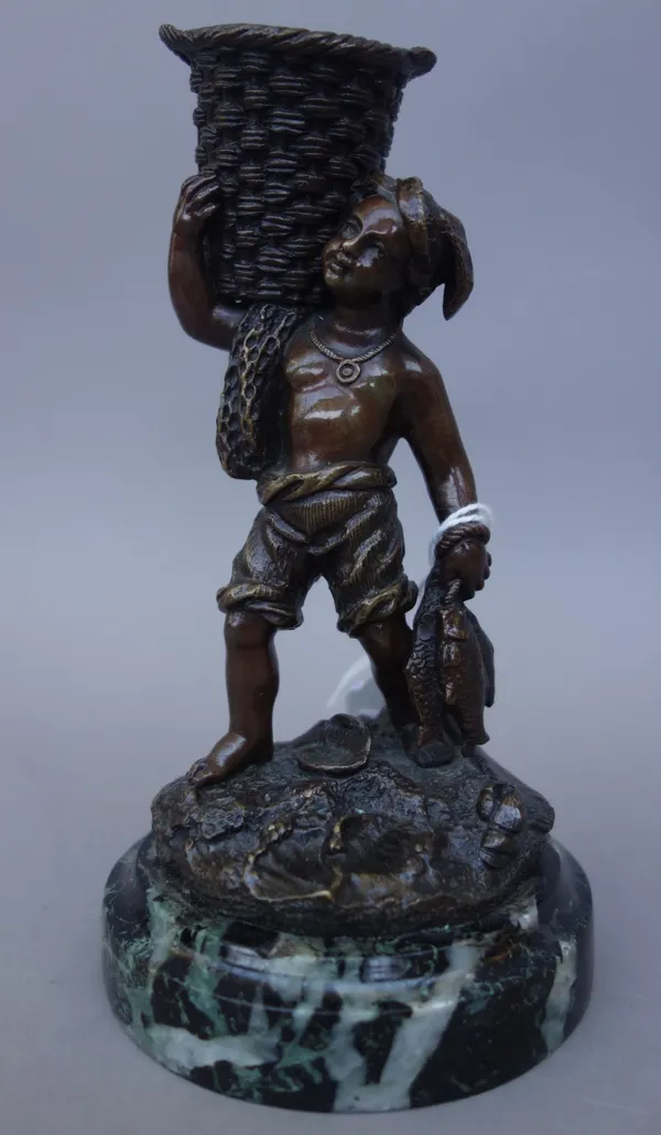 A Continental bronze figure, late 19th century, depicting a young fisherman with a basket on his shoulder, over a circular naturalistic base and green