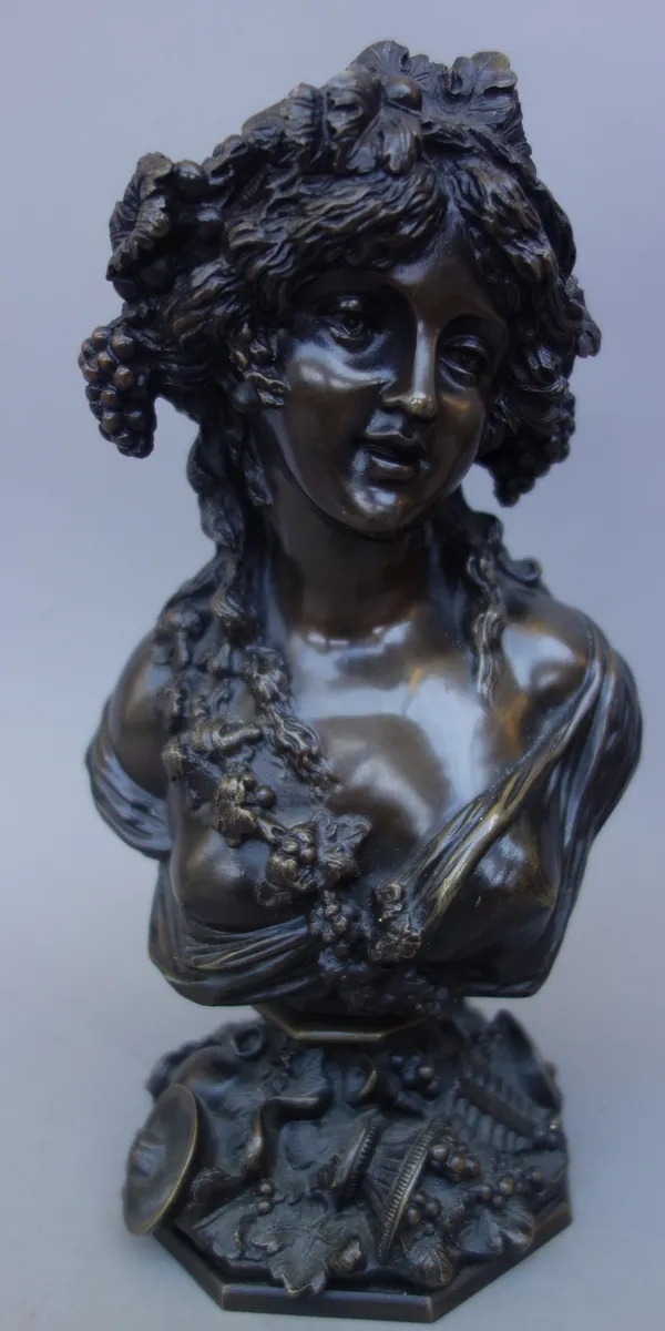 A Continental patinated bronze bust, late 19th century, depicting a scantily clad female emblematic of harvest season, on a naturalistic octagonal bas