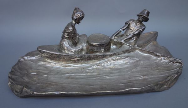 A silvered bronze inkwell and pen tray cast as a couple rowing, with central hinged inkwell, indistinctly signed to the rear, 39cm wide.   Illustrated