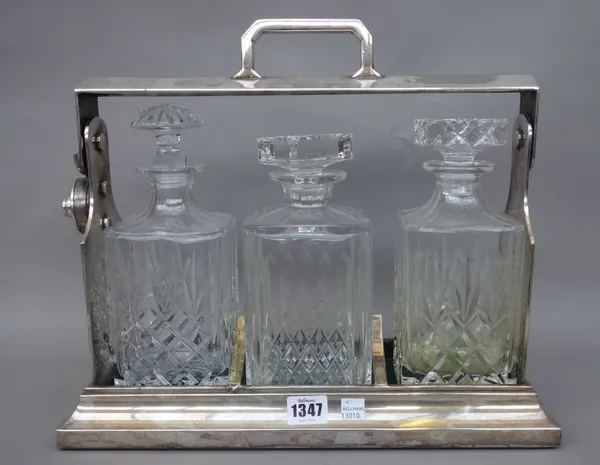 A silver plated three bottle tantalus, with locking mechanism and three associated glass decanters and stoppers, 38cm wide.
