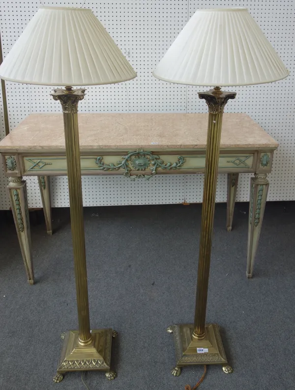 A pair of Victorian style brass standard lamps, 20th century, each of Corinthian column form, with cream silk pleated shades, 153cm high, (2).
