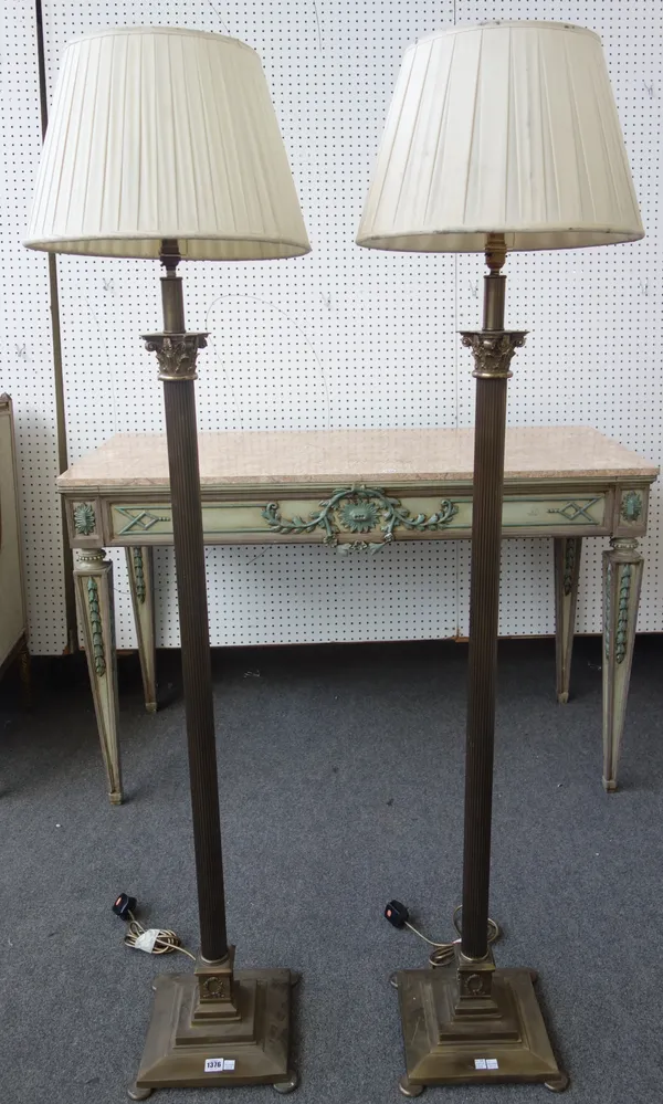 A pair of Victorian style brass standard lamps, 20th century, each of Corinthian column form, with cream silk pleated shades, 116cm high, (2).  AFTER