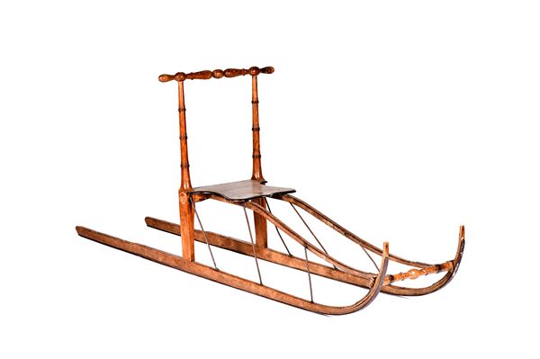 A bentwood sledge with turned handle and supports over a shaped seat with wrought iron supports to the runners, 220cm long.  Illustrated