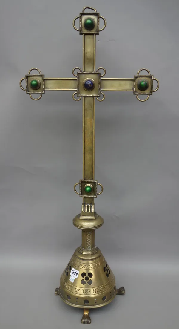 A Victorian brass altar crucifix, with applied coloured enamel cabochon over a pierced base, detailed 'In memory of the mission 1884', on three lions