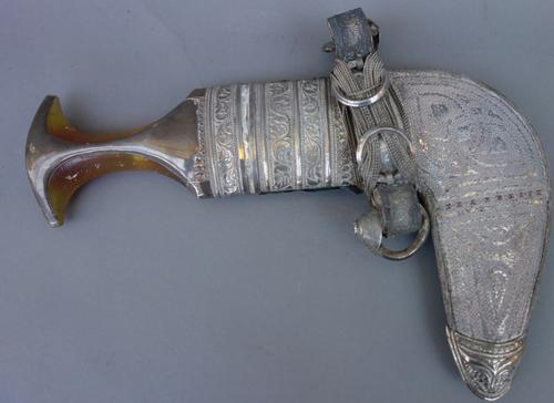 A Middle Eastern jambia with white metal mounts, and a South East Asian white metal opium pipe and pouch, (2).