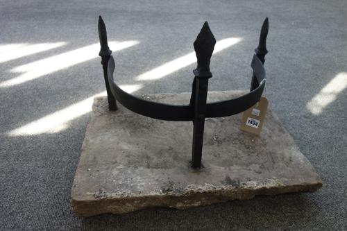 A Victorian cast iron boot scraper with three fleur-de-lys finials uniting a shaped stretcher on a later rectangular stone plinth. 54cm x 40cm.
