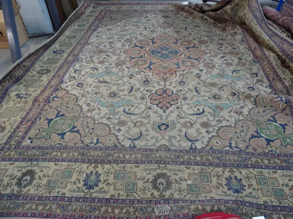 A Tabriz carpet, Persian, the ivory field with a bold apricot pole medallion, light brown spandrels, all with bold angular floral sprays, yellow palme