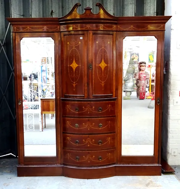 A late 19th century marquetry inlaid break bowfront compactum wardrobe, the swan neck cornice over a pair of panelled doors and four short drawers, fl