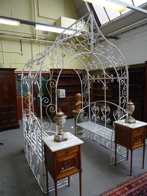 A 20th century wrought metal white painted rose arbour, with pointed top and pair of integral opposing benches, 174cm wide x 273cm high x 129cm long.