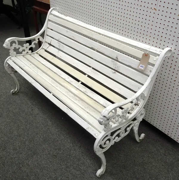 A white painted garden bench with slatted wood seat and cast metal supports with dogs head finials, 128cm wide x 80cm high.