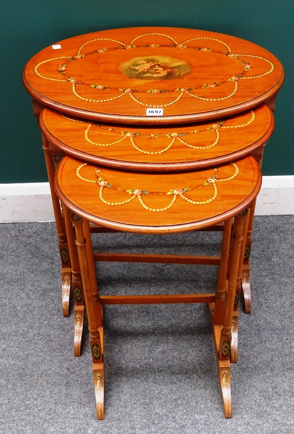 An Edwardian nest of three oval polychrome painted occasional tables, on turned supports, the larger 57cm wide x 65cm high x 38cm deep.