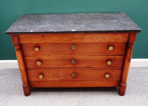 An early 19th century French commode, the rectangular marble top over a fruitwood four drawer base, flanked by turned columns, 130cm wide x 87cm high