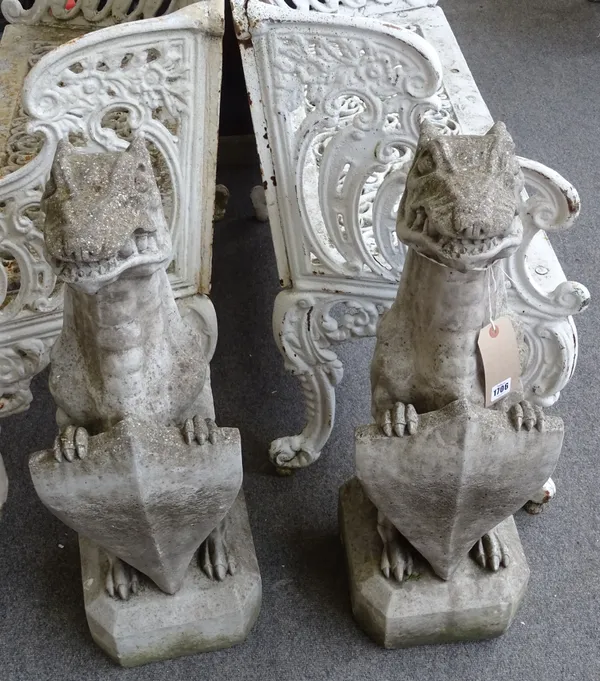 A pair of reconstituted stone finials, each modelled as a grotesque beast holding a shield, 27cm wide x 75cm high, (2).