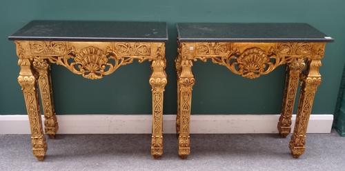 A pair of mid-18th century style consoles, each with rectangular black marble top, on a pierced and carved giltwood base and tapering square supports,