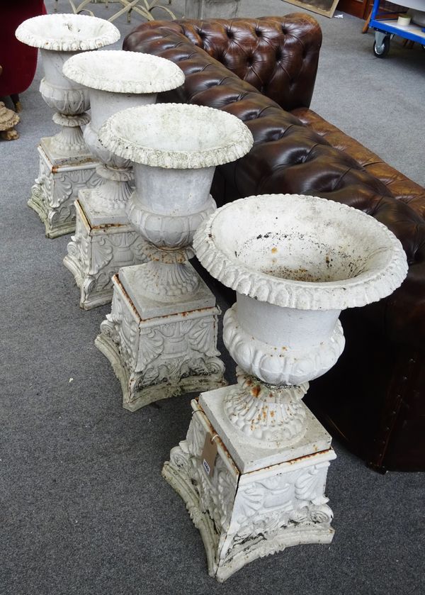 A set of four white painted cast iron garden urns, each with semi-lobed body on tapering shell moulded pedestal, 39cm diameter x 80cm high, (4).