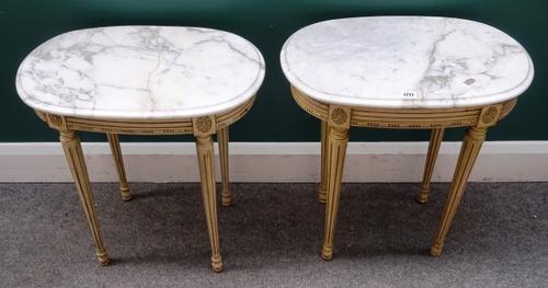 A pair of Louis XVI style occasional tables, each with oval marble top on four cream painted tapering fluted supports, 56cm wide x 58cm high x 36cm de