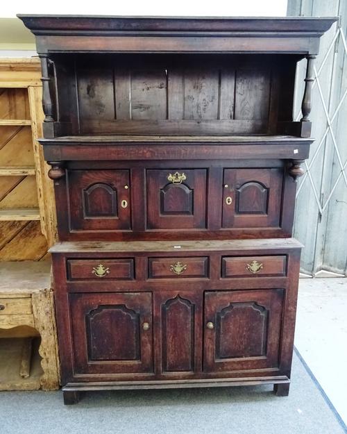 A mid-18th century oak tridarn/high dresser, with open top section above three arched panels, three drawers and a pair of lower cupboards, 137cm wide