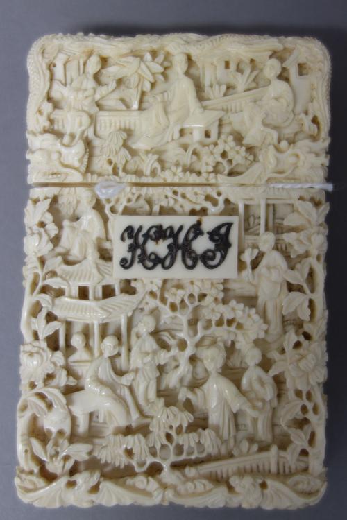 A Canton ivory rectangular card case and cover, late 19th century, well carved with figures at leisure amongst pavilions and trees, one side with a pa