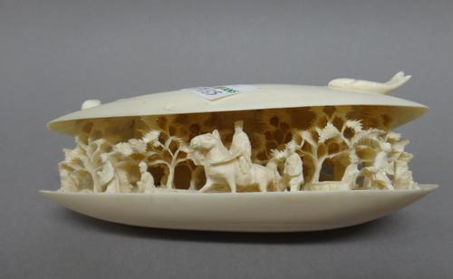 A Chinese ivory `clam's dream', early 20th century, the shell half open to reveal a figure on horseback and figures on foot amongst trees, 11.5cm. wid