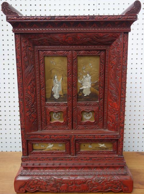 A Japanese red lacquer and shibayama two door table cabinet, Meiji period, of rectangular form, the doors decorated in ivory and mother-of-pearl with
