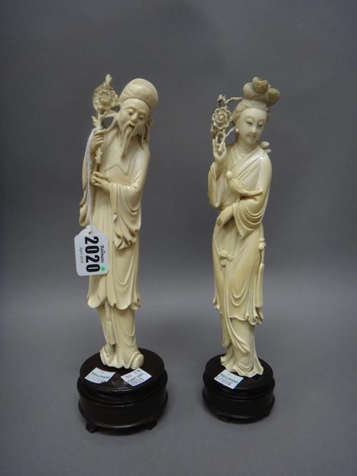 Two Chinese ivory figures of an old man and a young woman, early 20th century, each carved standing holding a flower spray, she with a bird on her lef