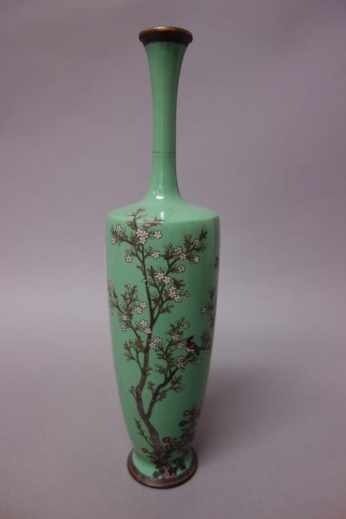 A Japanese cloisonné vase, Meiji period, worked with two birds amongst flowering branches against a green ground, 24.5cm. high.