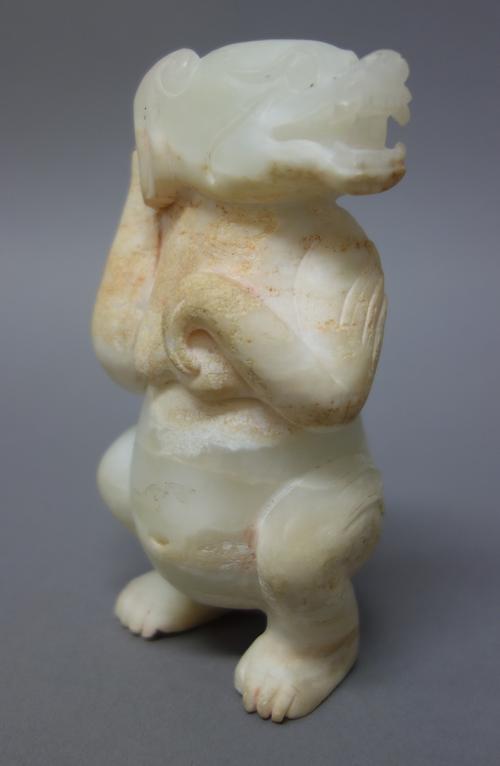 A Chinese archaistic jade carving of a female bear, carved crouching with her head turned towards her left, 13cm. high.