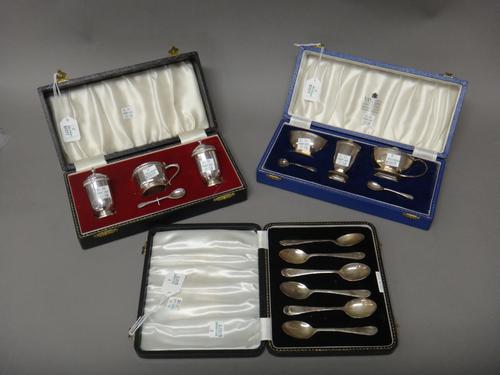 Silver, comprising; a three piece condiment set with two spoons, Birmingham 1959, with two blue glass liners, with a case, a three piece condiment set