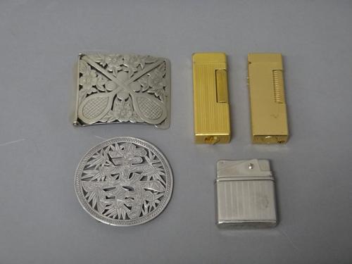 A rectangular waistbelt buckle, pierced and engraved with two tennis rackets, tennis balls and flowers, an Asian circular waistbelt buckle, two Dunhil