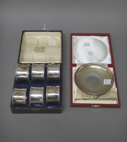 A set of six silver napkin rings, numbered 1-6 each with a wreath motif, Birmingham 1913, with a case and a silver circular dish, mounted to the centr