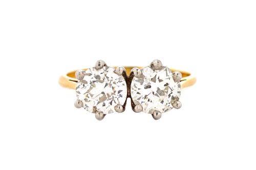 An 18ct gold and diamond two stone ring, claw set with cushion shaped diamonds, in a later setting, London 1988, the diamonds weigh approx 0.80 cts ea