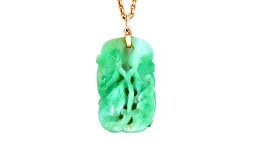 An Asian carved jade pendant, in a pierced foliate design, with a gold oval link neckchain, on a boltring clasp, weight of chain 9.5 gms.  Illustrated