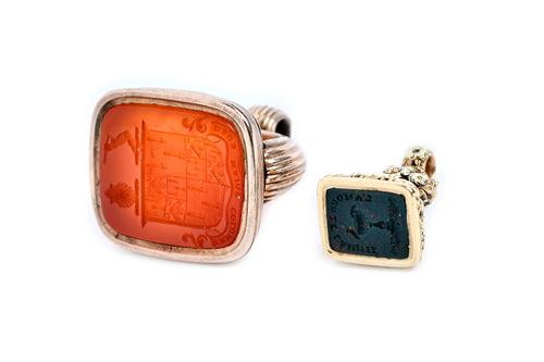 An early 19th century cornelian set pendant fob seal, seal engraved with a shield, twin crests and a motto and a bloodstone set smaller pendant fob se