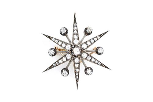 A diamond brooch, designed as a six pointed starburst, mounted with cushion shaped and rose cut diamonds, with the principle diamond mounted to the ce