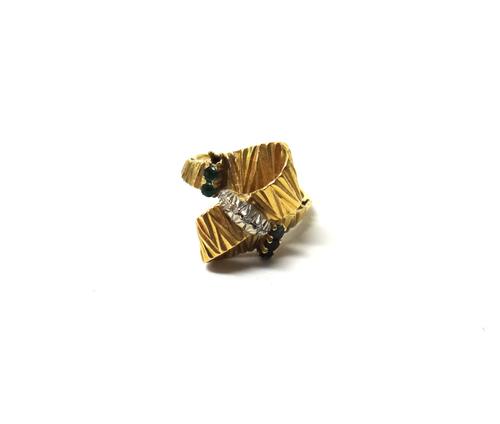 A gold, diamond and emerald set ring, in a twist over design mounted with a row of three circular cut diamonds to the centre, between emerald set side