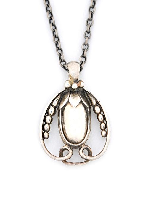A Georg Jensen silver pendant, formed as a bud within an open scrolling surround, detailed Georg Jensen 1990, import mark London 1990, with a neckchai