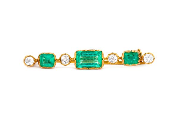 A gold, emerald and diamond seven stone bar brooch, mounted with the rectangular step cut principal emerald to the centre and further set with two sma