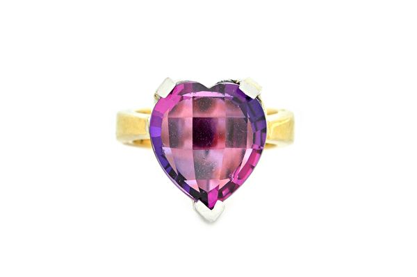 A two colour gold and synthetic mauve coloured corundum single stone ring, claw set with a faceted heart shaped gem, the mount un-marked, gross weight