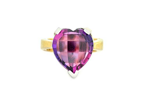 A two colour gold and synthetic mauve coloured corundum single stone ring, claw set with a faceted heart shaped gem, the mount un-marked, gross weight