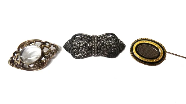 A Victorian shaped oval brooch, glazed with a central locket compartment, within a scroll pierced surround, a gilt metal and black enamelled oval mour