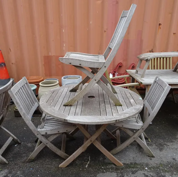 A 20th century hardwood circular folding garden table 109cm wide x 73cm high, together with three folding garden chairs, (4).  OUT