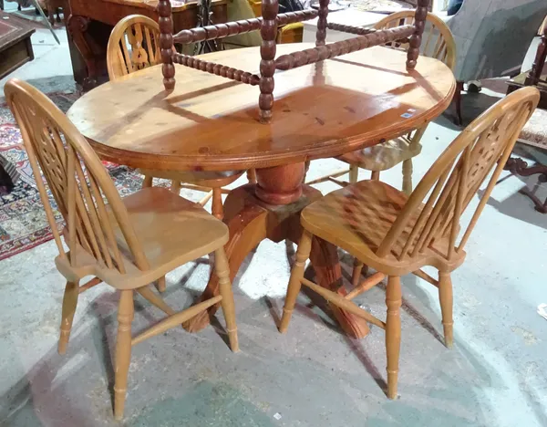 A 20th century oval pine dining table, 137cm wide x 85cm high, together with four wheel back dining chairs, (5).  H3