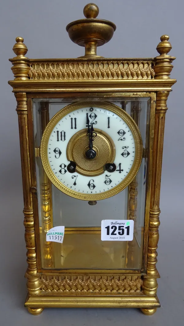 A regency style brass, four glass mantel clock, circa. 1900, with urn finial and pillared supports enclosing a two train movement with hammer chiming
