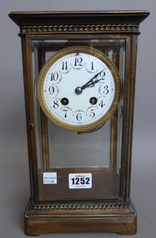 A French brass four glass mantel clock, early 20th century, with foliate painted enamel dial and two train movment with hammer striking a coiled gong,