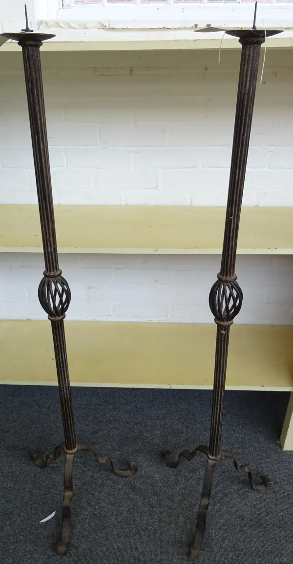 A pair of 16th century style wrought iron altar candlesticks, modern, of fluted form, with open frame knopped stem on three feet. 131cm high. (2)